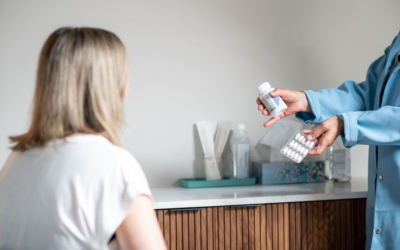 Woman in clinic room looking at a doctor who is holding out two types of probiotic products